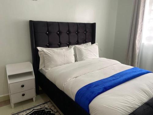 a bedroom with a large bed with a blue blanket at Garden estate Thika road furnished home in Nairobi