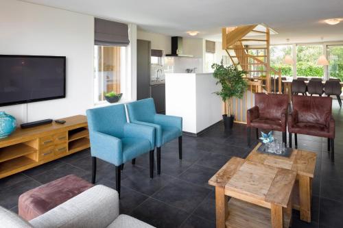 een woonkamer met blauwe stoelen en een flatscreen-tv bij Summio Waterpark Zwartkruis in Noordbergum