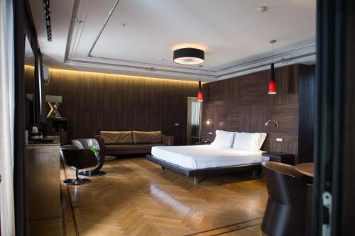 ローマにあるDivina Luxury Hotelのベッドとソファ付きのホテルルーム