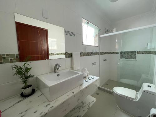 a white bathroom with a sink and a toilet at Aires de geribá in Búzios