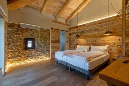 1 dormitorio con cama y pared de piedra en Chalet l'ozio creativo, en Castelnuovo Nigra