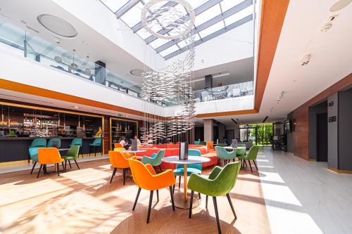 a restaurant with colorful chairs and tables in a building at Hotel Helikon, Keszthely in Keszthely