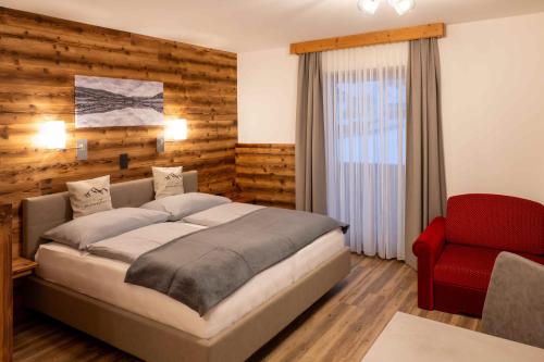a bedroom with a bed and a red chair at Pension Kreischberg Mayer in Sankt Lorenzen ob Murau