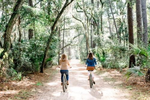 two girls riding bikes down a dirt road in a forest at Montage Palmetto Bluff in Bluffton