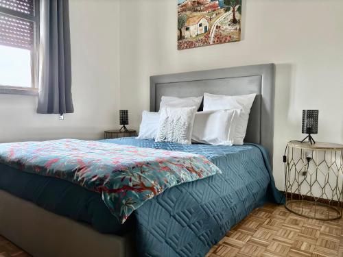 uma cama com um edredão azul e almofadas brancas em Vale a Pena Residencial em Trancoso