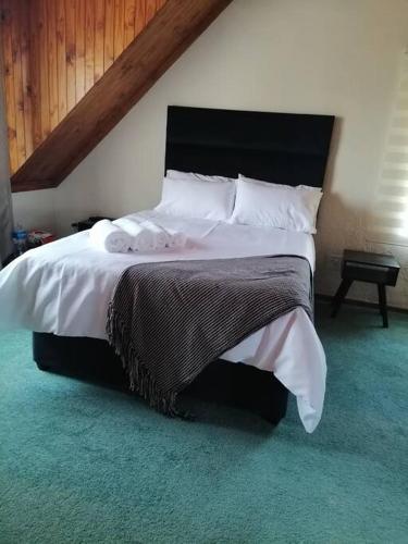 a bedroom with a large bed with white sheets and pillows at Traveller's dream in Graskop