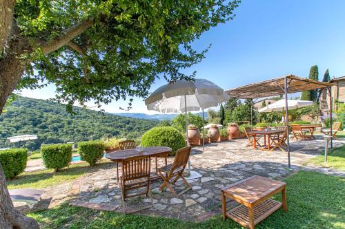 patio ze stołami, krzesłami i parasolami w obiekcie Agriturismo Fattoria Santo Stefano w Greve in Chianti