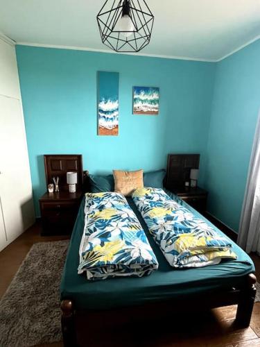 a blue room with a bed with pillows on it at Kleines Haus am Meer in Arco da Calheta