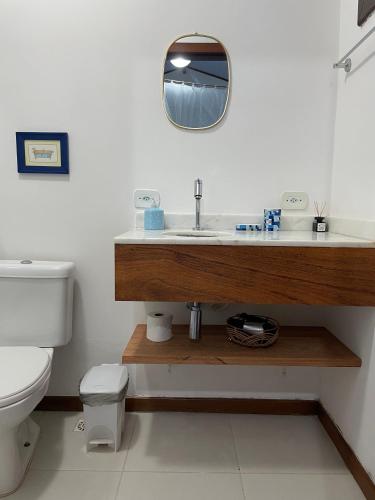 a bathroom with a sink and a toilet and a mirror at Casa Jasmim Imbassaí-BA in Mata de Sao Joao
