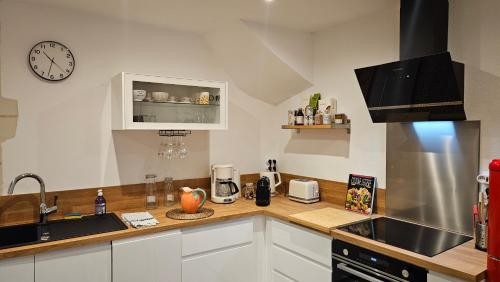 - une cuisine avec des placards blancs, un évier et une horloge dans l'établissement Duplex élégant Tours quais de Loire, à Tours