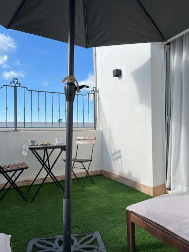 an umbrella on a balcony with a table and chairs at Hotel San Miguel Menorca in Mahón