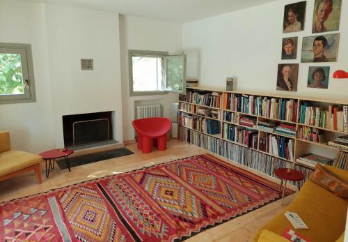 a living room with a red stool and bookshelves at lassù minihotel 