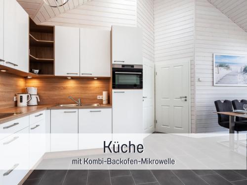 a kitchen with white cabinets and a table and chairs at Ferienhaus Küstenzauber Kalifornien - mit Hund - komplett eingezäunter großer Garten - Sauna und Kamin - im Sommer Strandkorb inklusive in Schönberg in Holstein
