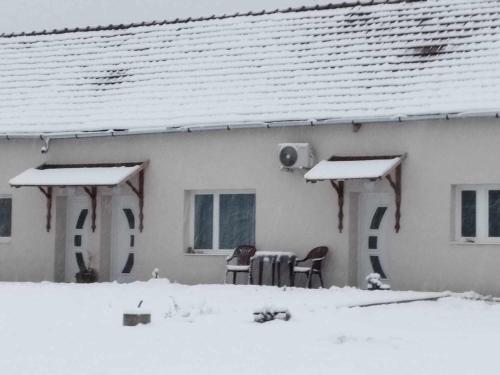 a house with a table and chairs in the snow at Aba-Böbe Vendégház in Zalaszentiván