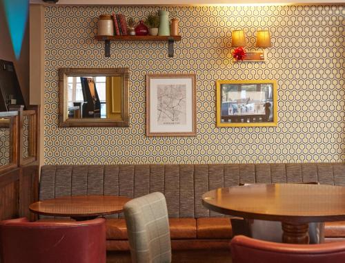 a restaurant with two tables and two mirrors on the wall at The Quays by Greene King Inns in Northampton