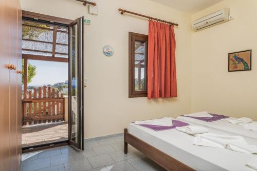a bedroom with a bed and a window and a balcony at Vigla-Βίγλα 1 2 in Órmos Marathokámpou