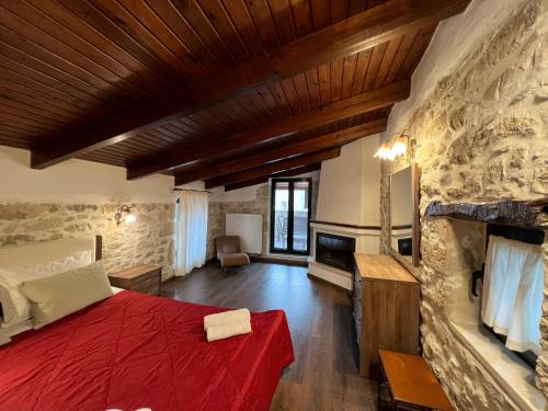 1 dormitorio con cama roja y pared de piedra en Pyrgou Villa Spacious and Unique 1, en Pirgoú