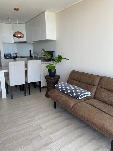 uma sala de estar com um sofá e uma cozinha em Departamento Vista al mar con estacionamiento em Concón