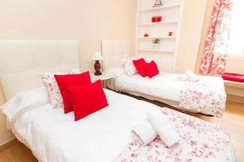 2 camas en una habitación con almohadas rojas y blancas en Piso junto a la Catedral, 4-5 personas, en Málaga