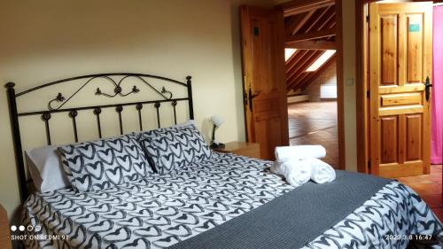 a bed with a black and white comforter and pillows at Albergue Valle de Tobalina in Quintana-Martín Galíndez