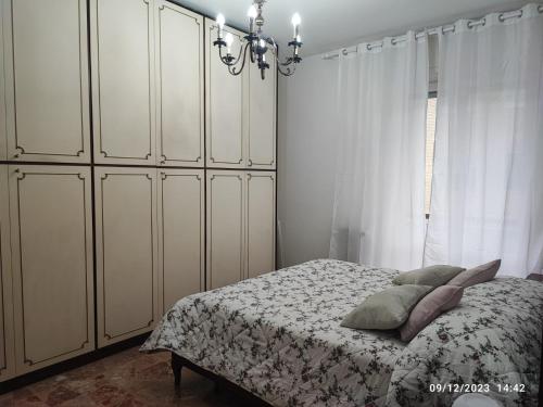 a bedroom with a bed with white cabinets and a chandelier at CASA DI LORY in Milan