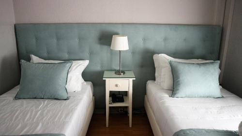a bedroom with two beds and a lamp on a side table at Hotel Senhor de Matosinhos in Matosinhos