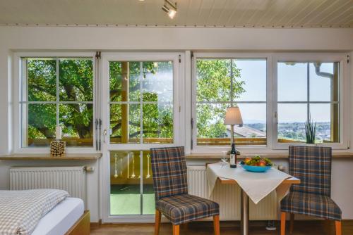 - une chambre avec une table, des chaises et des fenêtres dans l'établissement Ferienhof Walter, à Fribourg-en-Brisgau