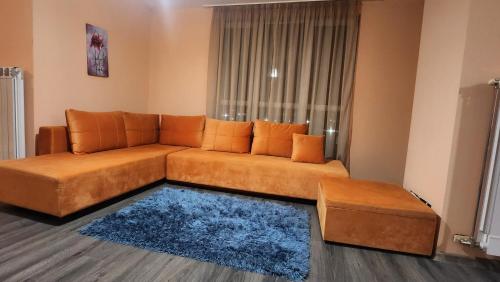 ein Wohnzimmer mit einem braunen Sofa und einem blauen Teppich in der Unterkunft Елегантен градски апартамент с обширна тераса in Pernik