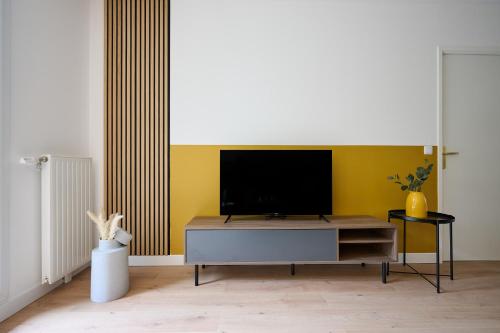 een woonkamer met een flatscreen-tv aan een gele muur bij YELLOW House - Terrasse - Proche Paris et transports - Tout équipé in Montfermeil