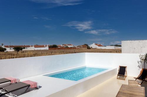 a swimming pool on a white wall with two chairs at Villas Mont-Blanc in Reguengos de Monsaraz
