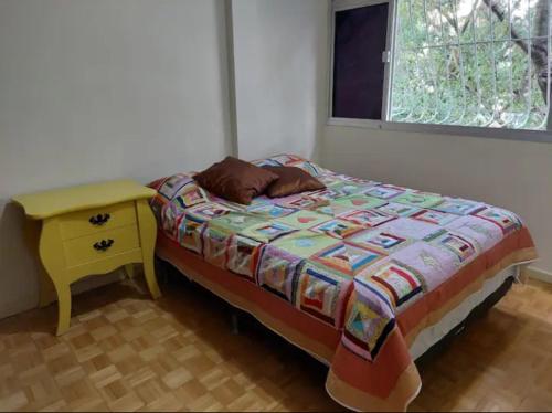 a bedroom with a bed and a table and a window at Quarto in Vitória