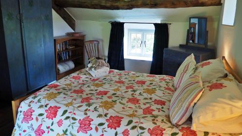 a bedroom with a bed with a floral bedspread at Finest Retreats - Woodend - The Cottage in Ulpha