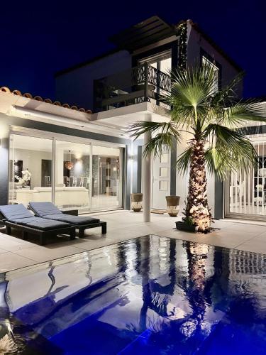 une maison avec un palmier en face d'une piscine dans l'établissement suite détente, à Maussane-les-Alpilles