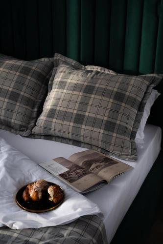 a plate of food on a bed with pillows and a book at Alpina Residence & Kameralne SPA in Bukowina Tatrzańska