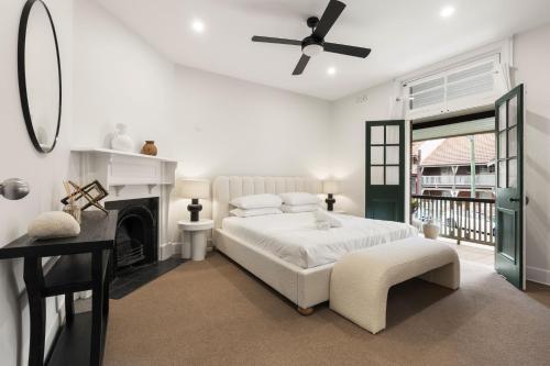 a white bedroom with a bed and a fireplace at Stunning Terraced Apartment near the Sydney Opera House in Sydney