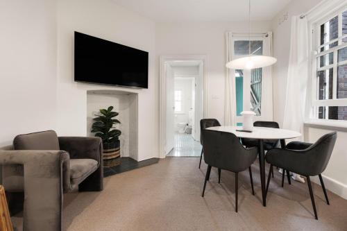 a living room with a table and chairs and a tv at Stunning Terraced Apartment near the Sydney Opera House in Sydney