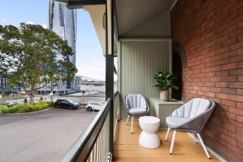 a balcony with two chairs and a brick wall at Stunning Terraced Apartment near the Sydney Opera House in Sydney