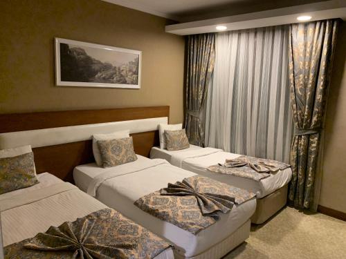 a hotel room with three beds and a window at MOONLİGHT HOTEL in Bostaniçi