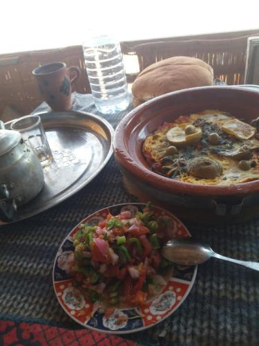 una mesa con un plato de comida y un plato de comida en Raha Cave Said, en Douaïra