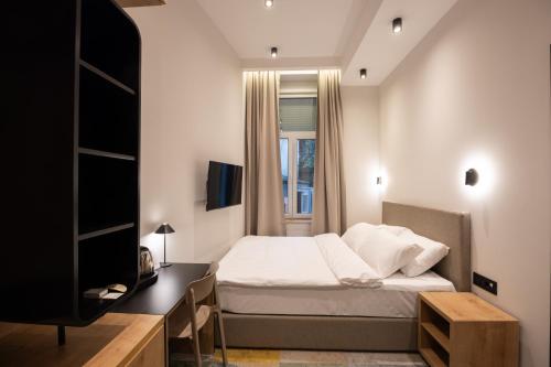 een slaapkamer met een bed, een bureau en een televisie bij Hop Inn Rooms & Suites in Belgrado