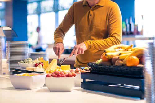 a man is preparing food on a counter with fruits and vegetables at Hotel Helikon, Keszthely in Keszthely