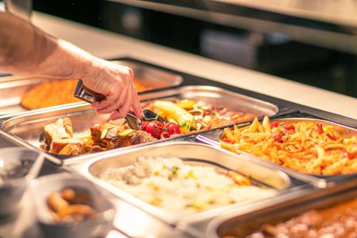 a person is reaching for a tray of food at Hotel Helikon, Keszthely in Keszthely