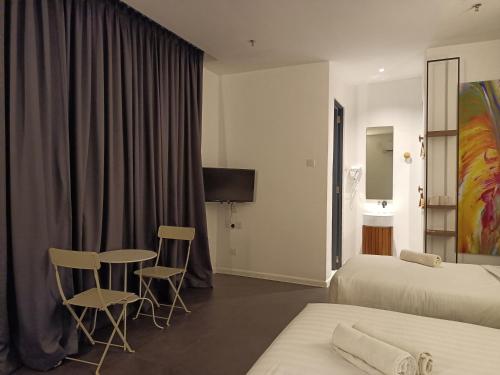 アロースターにあるT+ PREMIUM HOTELのベッド2台、テーブルと椅子が備わるホテルルームです。