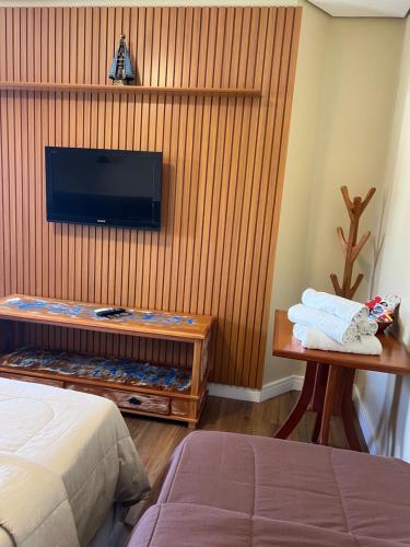 um quarto com uma cama e uma televisão na parede em Rogai Hotel Pousada em Aparecida