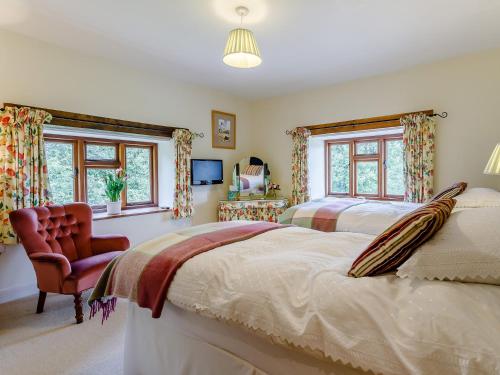 a bedroom with two beds and a chair and windows at 5 Bed in Bampton GRACI in Oakford