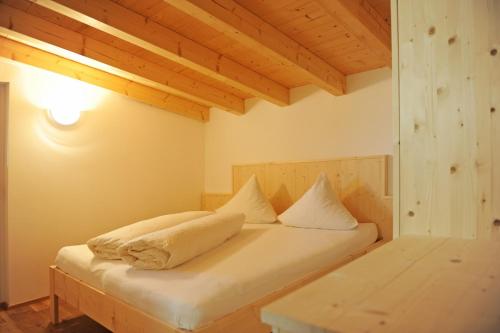 a bed with white sheets and pillows in a room at Pension Olympia in Oetz