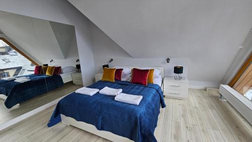 a bedroom with two beds with blue and red pillows at Apart4You Apartamenty Bory Sweet Time in Zakopane