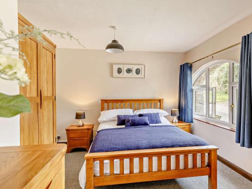 a bedroom with a wooden bed with blue pillows at 2 Bed in South Molton 88994 in Bishops Nympton