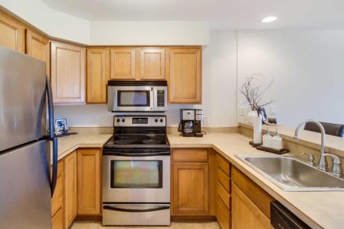 a kitchen with wooden cabinets and stainless steel appliances at Beautiful Bigfork Condo with Hot Tub Access! in Bigfork