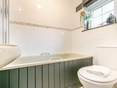 a bathroom with a green and white tub and a toilet at 1 Bed in Crackington Haven HAWTH in Saint Gennys